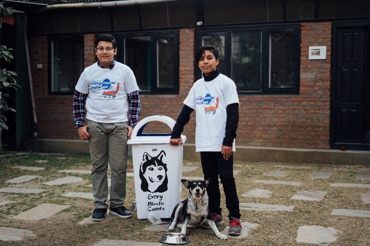 Two boys standing next to a bin with a dog's face on it